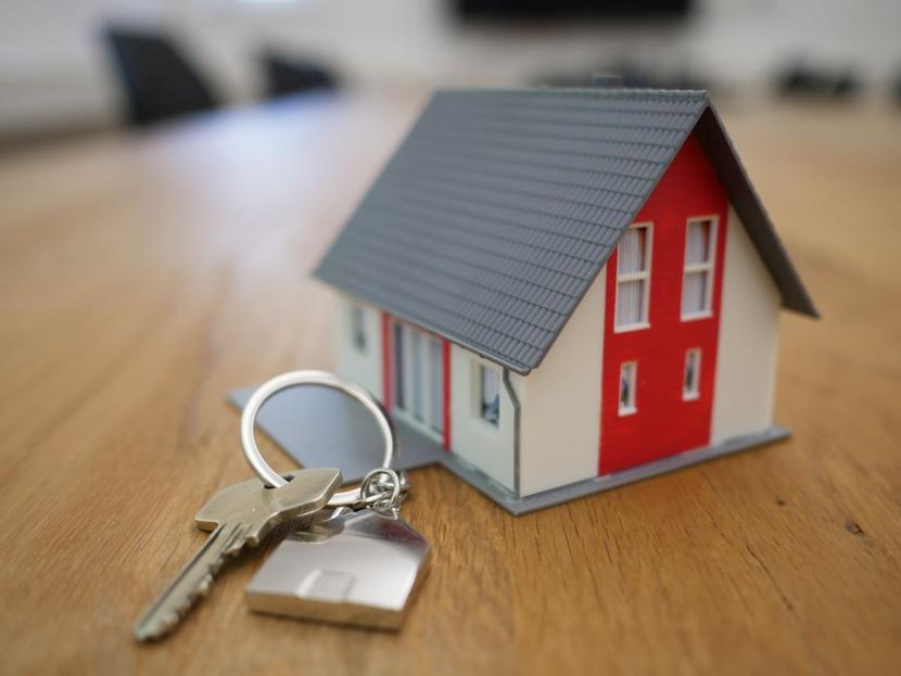 Maqueta de una casa pequeña con llaves sobre una mesa de madera 