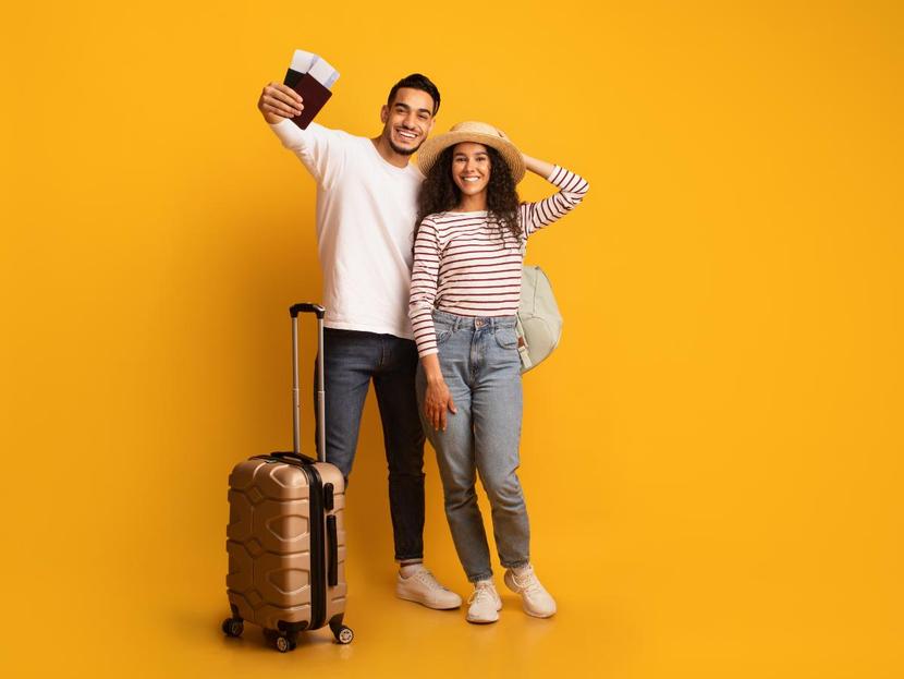 Feliz pareja con pasaporte en mano y maletas 