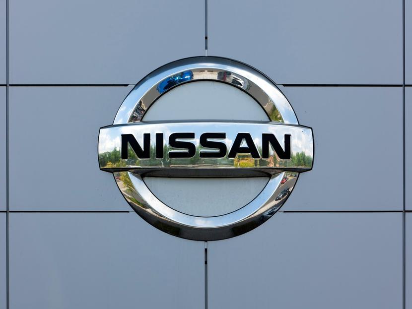 Logotipo de la marca de autos Nissan en color plateado sobre una pared. 