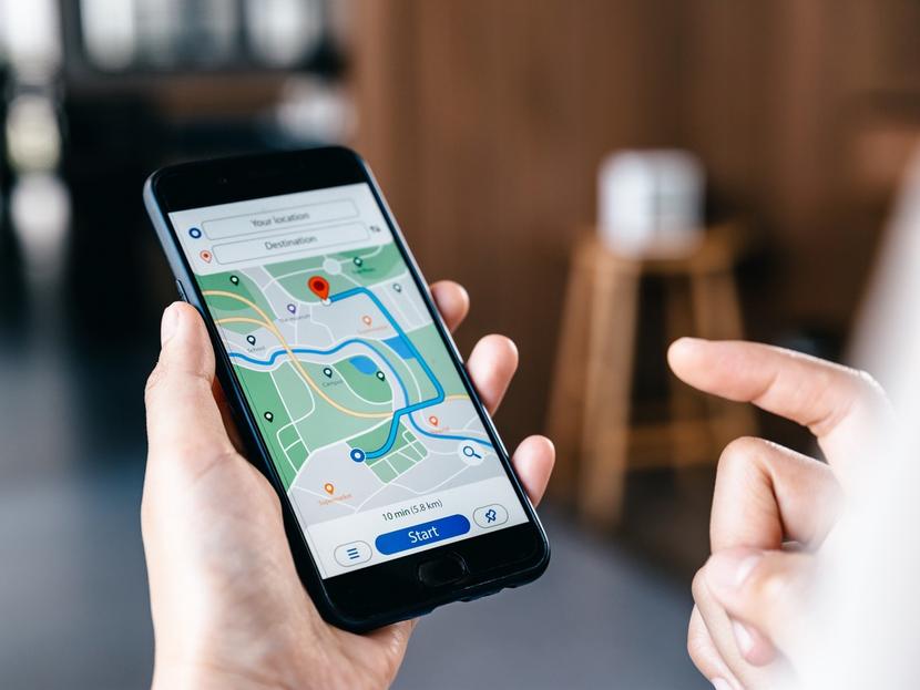 Las manos de una persona utilizan un celular que muestra mapa de Google en la pantalla. 