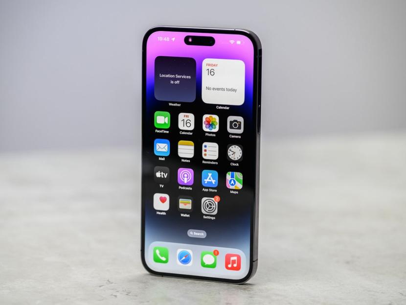 La pantalla principal de un iPhone colocado sobre una superficie color gris. 