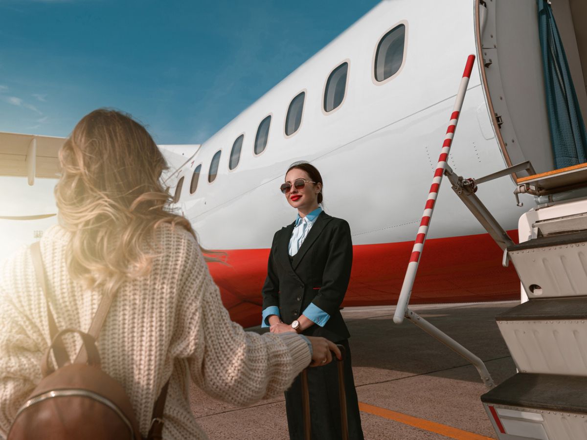 Mujer azafata de pie cerca del avión 