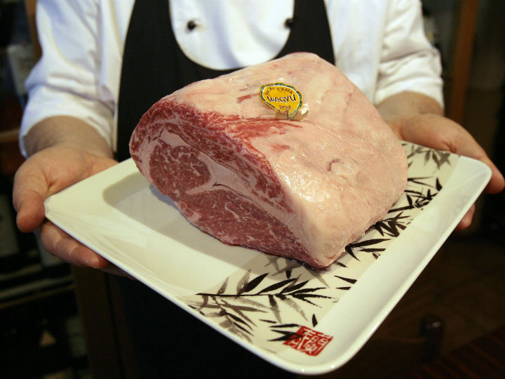 corte de carne kobe rosada mostrada por un chef