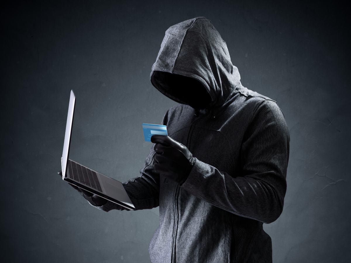 Hacker sosteniendo pc portátil y tarjeta de crédito. 