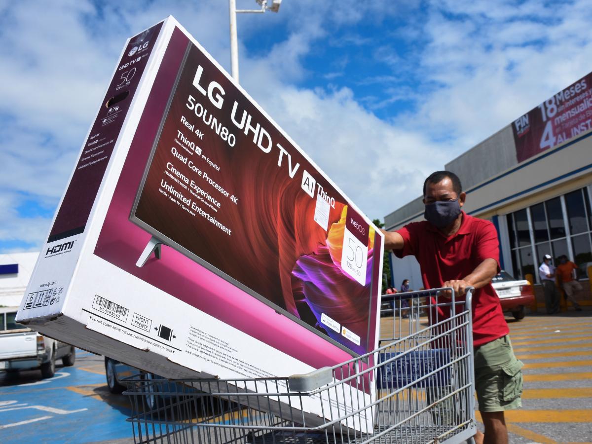 Hombre con una Smart TV en un carrito de supermercado 