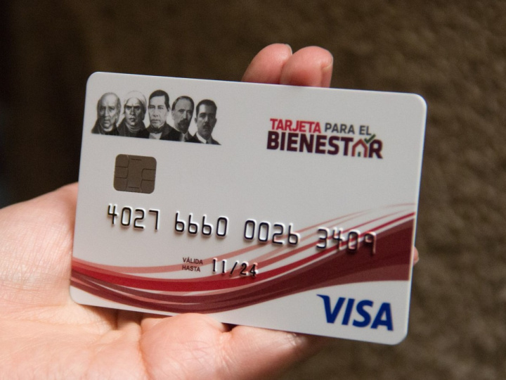 Una mano sostiene una tarjeta bancaria blanca del Banco del Bienestar y VISA. 