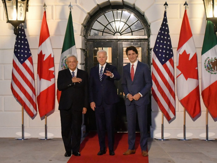López Obrador, Joe Biden y Justin Trudeau posando para la foto, detrás hay banderas de México, Estados Unidos y Canadá. 