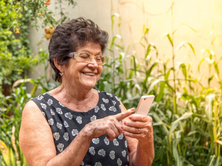 Mujer mayor con celular para que tu abuelito se mantenga comunicado 