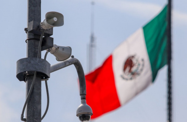 Bocina de alerta sísmica en ion poste callejero y con la bandera de México al fondo. 