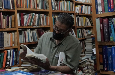 Hombre en librería sosteniendo libro abierto
