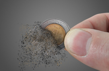 Unos dedos sostiene una moneda de 1 peso mexicano que se está deshaciendo. 