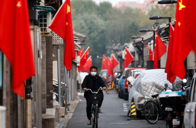 Persona en bicicleta en calles de China con banderas de china