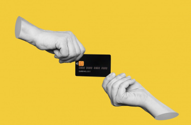 Dos manos sostienen una tarjeta de crédito negra y un fondo color amarillo. 
