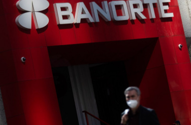 La entrada de una sucursal bancaria de Banorte con una persona caminado afuera. 