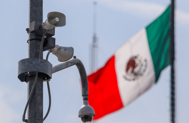 Bocina de alerta sísmica colocada sobre un poste, al fondo se observa la bandera de México. 