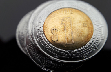 Pila de monedas de un peso mexicanos en un fondo color negro. 