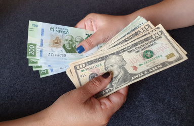 Manos de mujeres intercambian billetes mexicanos y dólares 