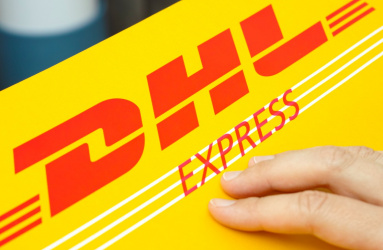 Un sobre amarillo de la marca DHL con una mano encima. 