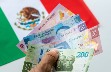 Mano con dinero en mano y bandera de México de fondo esperando comprar en una de las ciudades más baratas
